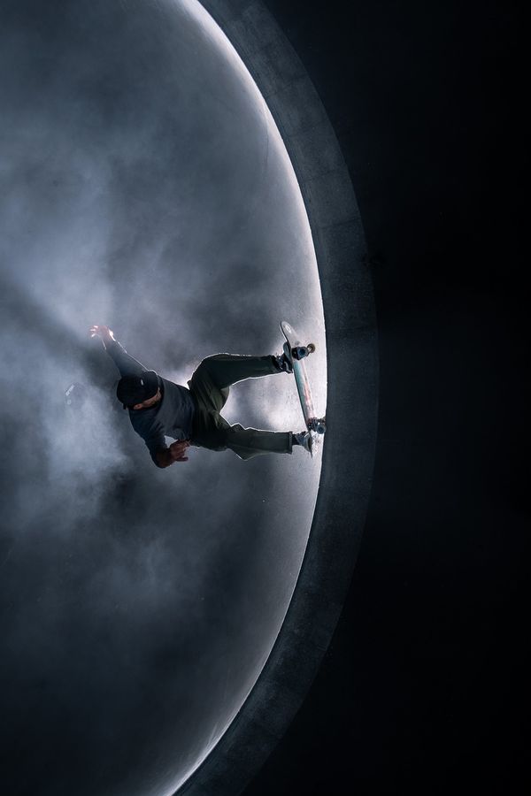 Overhead view of a skater carving a bowl wall through smoke