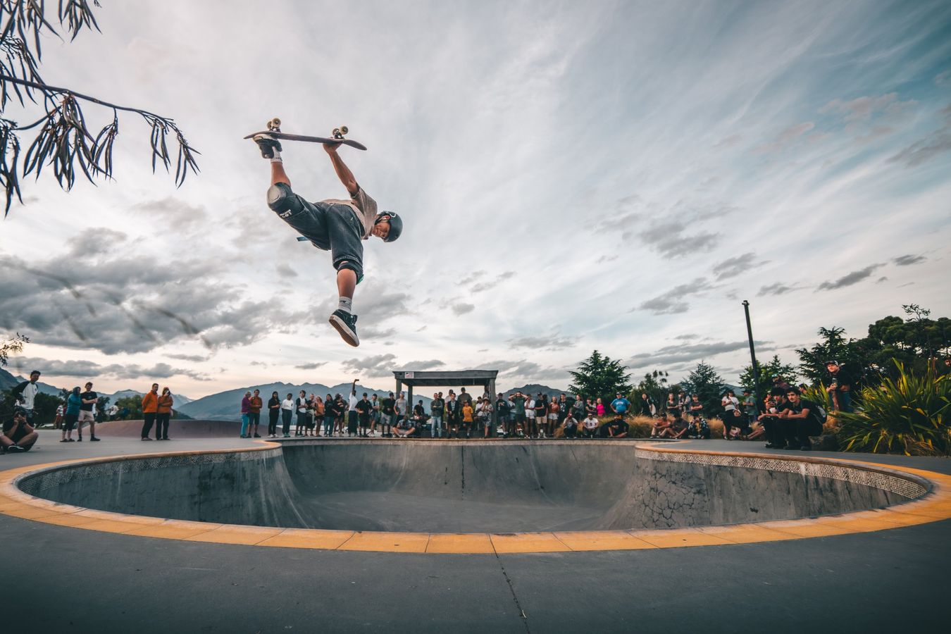 Skater upside down above a bowl with a crowd watching